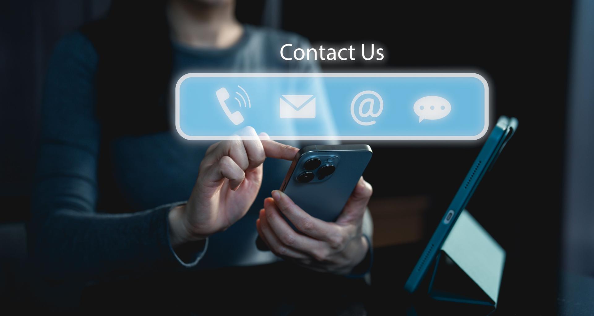 A person interacts with a smartphone displaying a "Contact Us" interface, featuring icons for phone, email, and chat options.